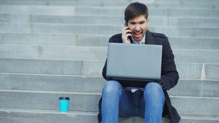 Man on phone with laptop on stairs